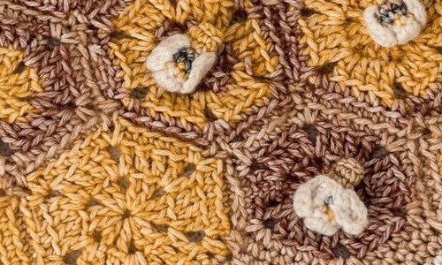 A close-up of the finished blanket showing the hexagon stitches and bee detailing.